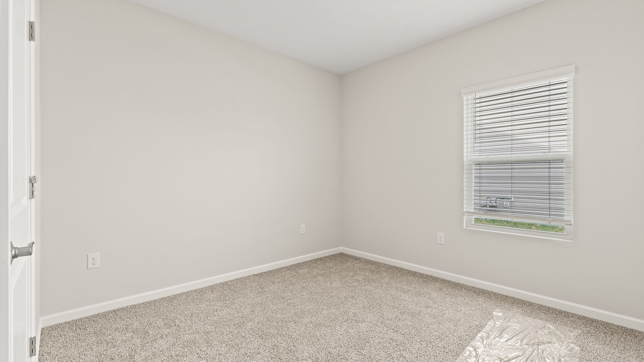 Carpeted bedroom with white walls and window.