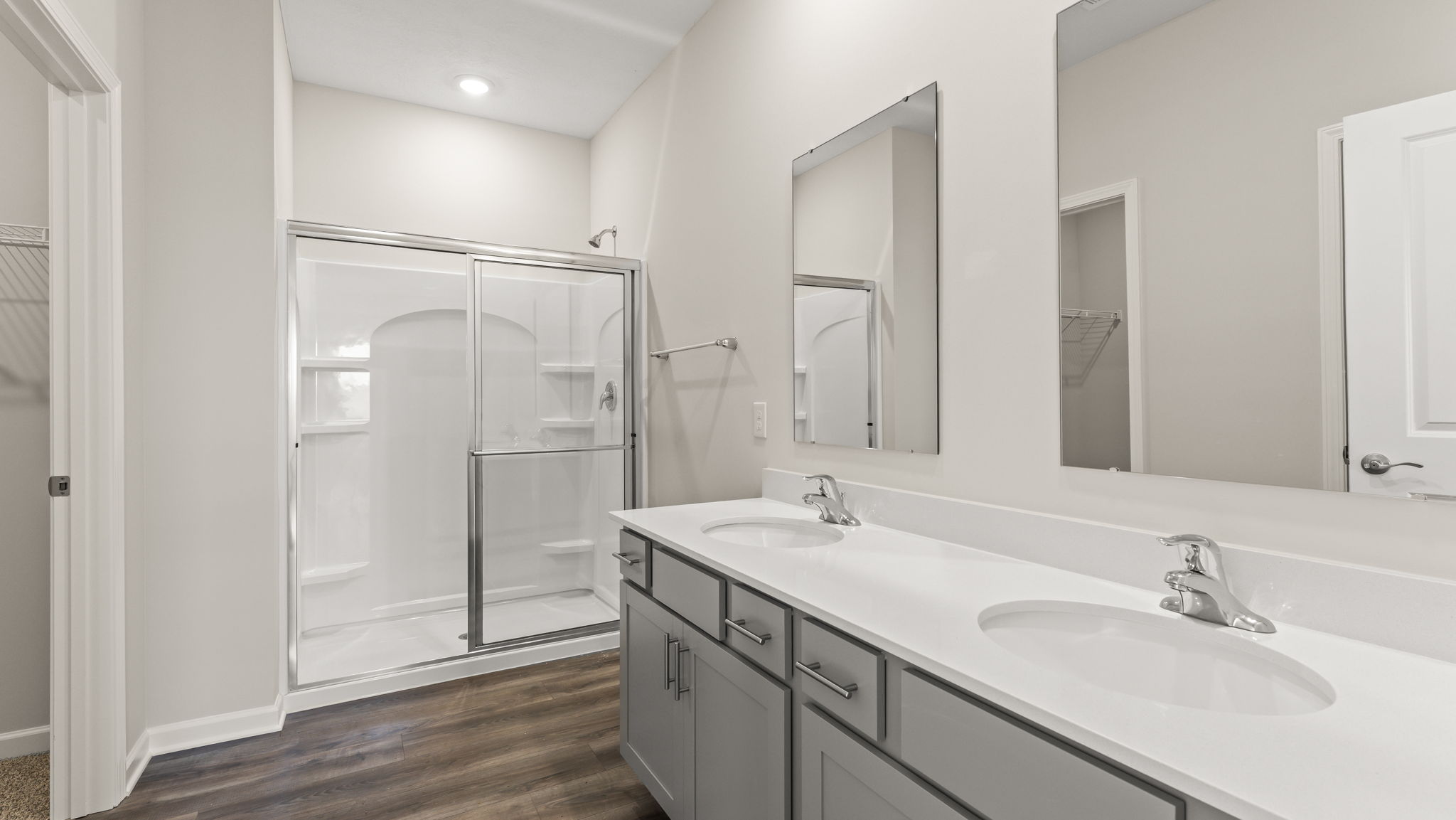 Primary bathroom with white countertops, dual-sink vanity, and walk-in shower.