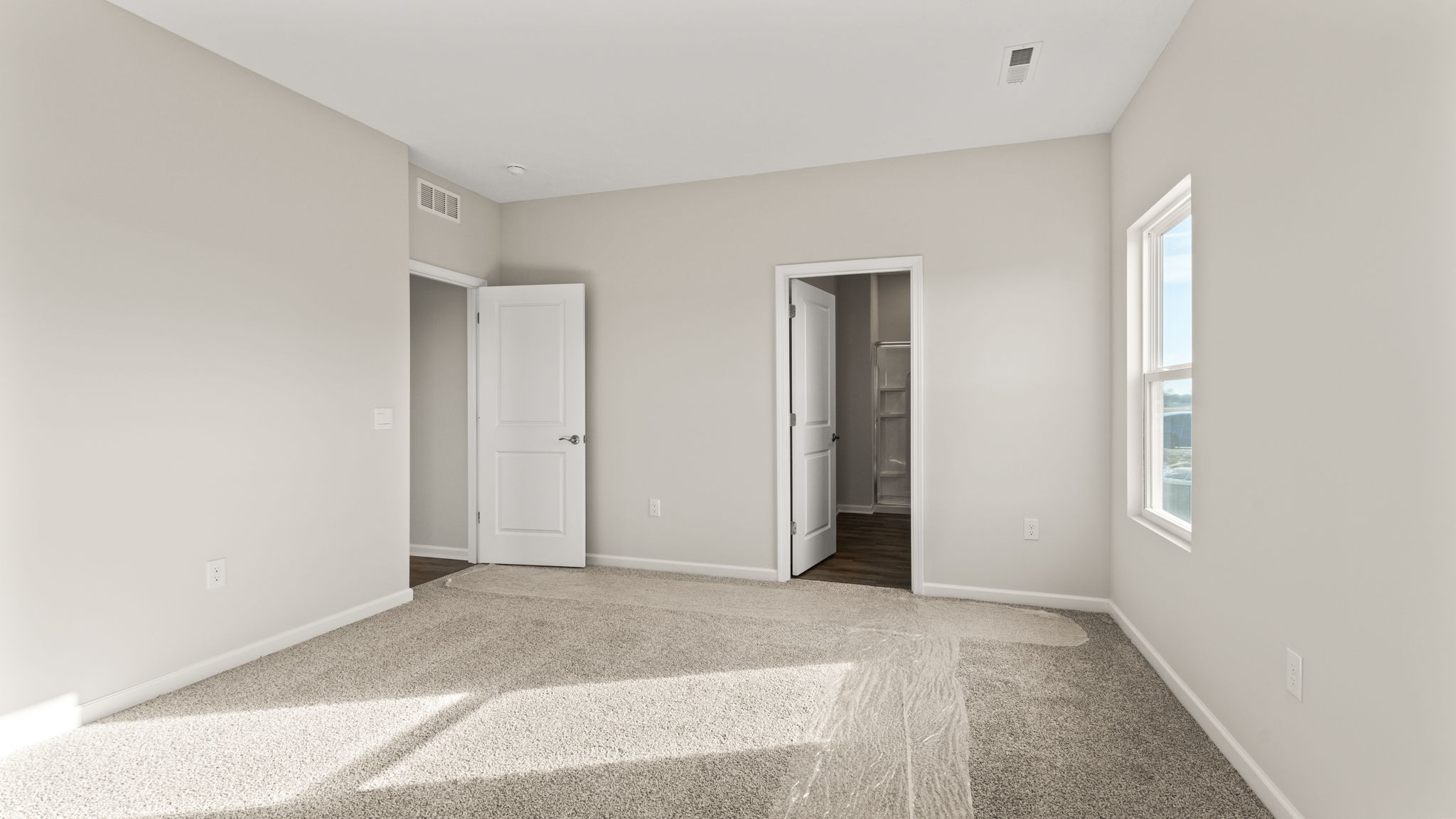 View of primary bedroom with primary bathroom in the back