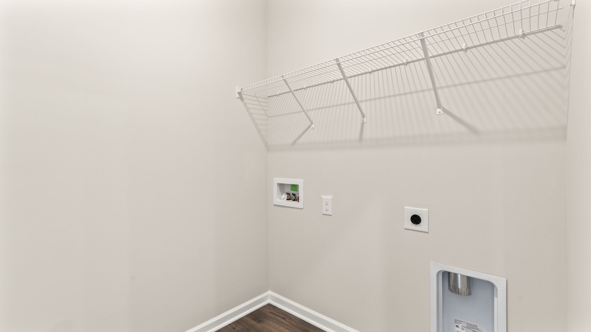 Launry area with shelving and washer/dryer inlets.