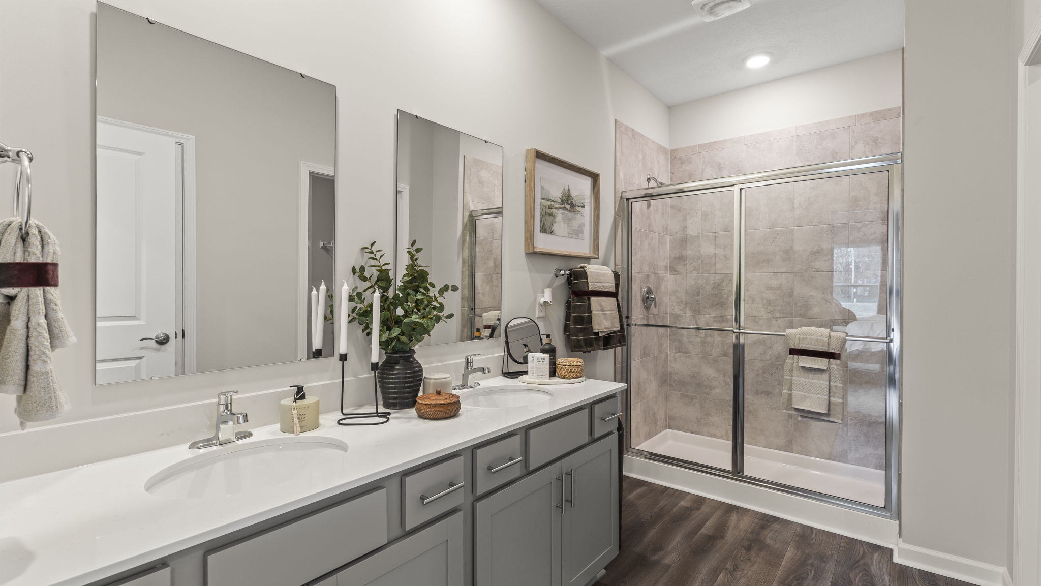 Full primary bathroom with double-sink vanity and mirrors with walk-in shower.