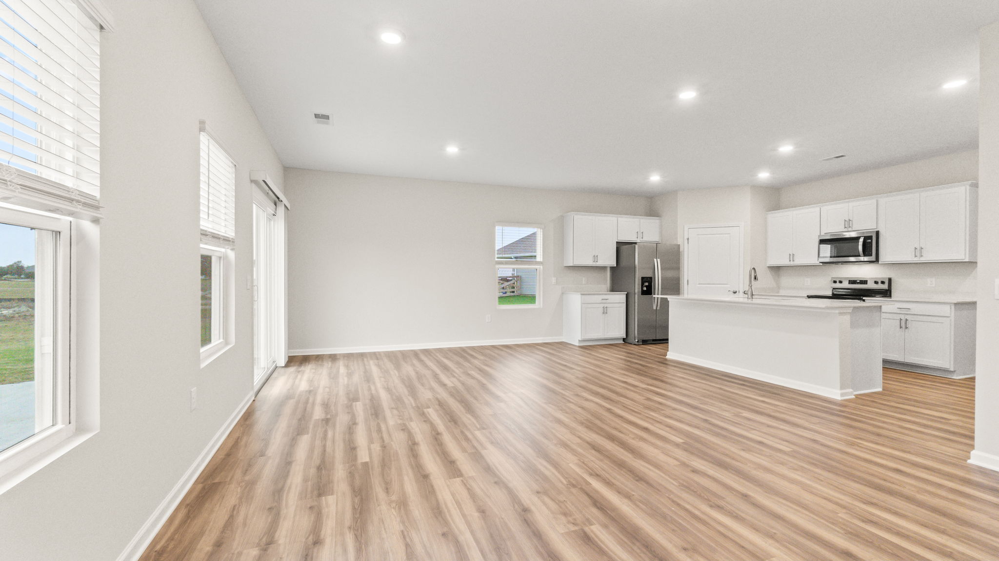 Full great room and kitchen area with wood-look flooring and natural lighting