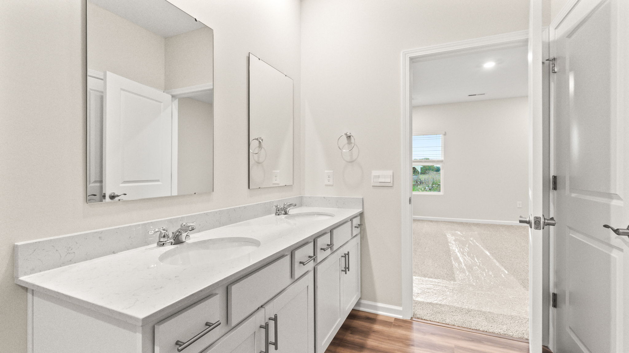 Primary bathroom suite with dual sink and mirror vanities