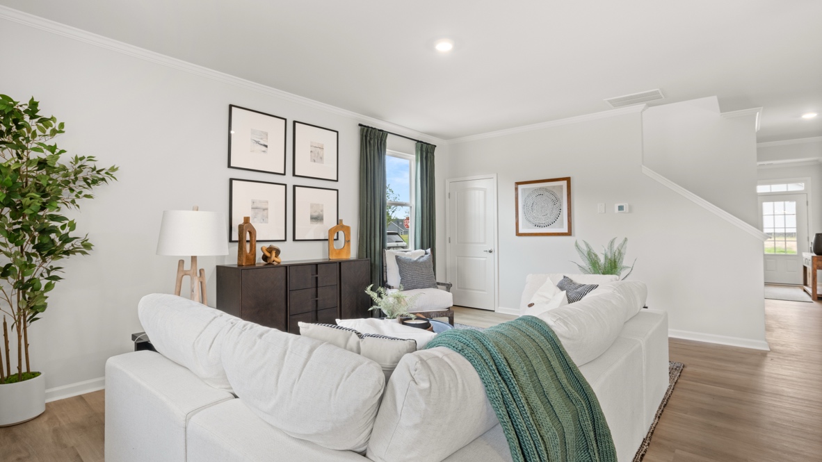 Three-quarter view of living room from behind white couch with green throw pillow