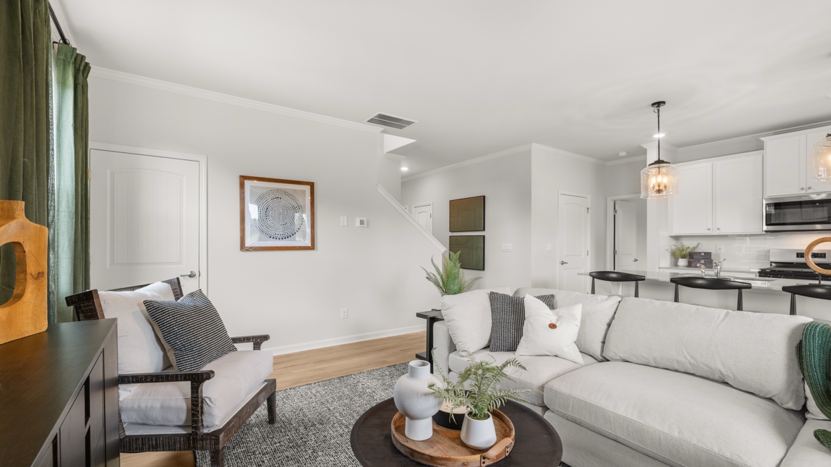 Green and brown themed contemporary living room with white couches and coffee table with plant