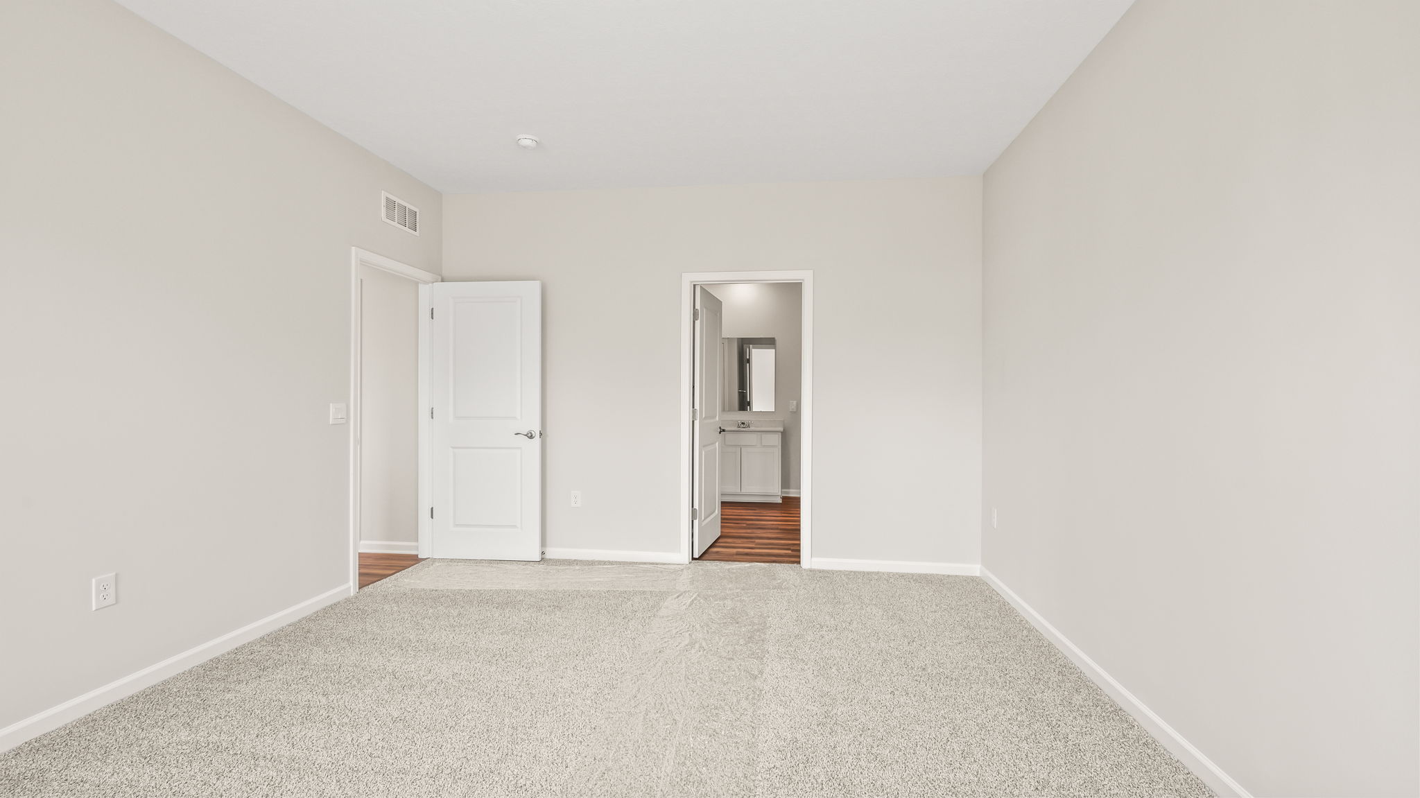 carpeted primary bedroom with door to bathroom suite