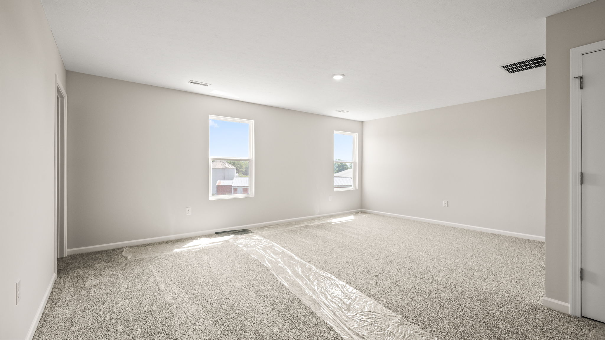 Wide angle image of carpeted loft with two windows