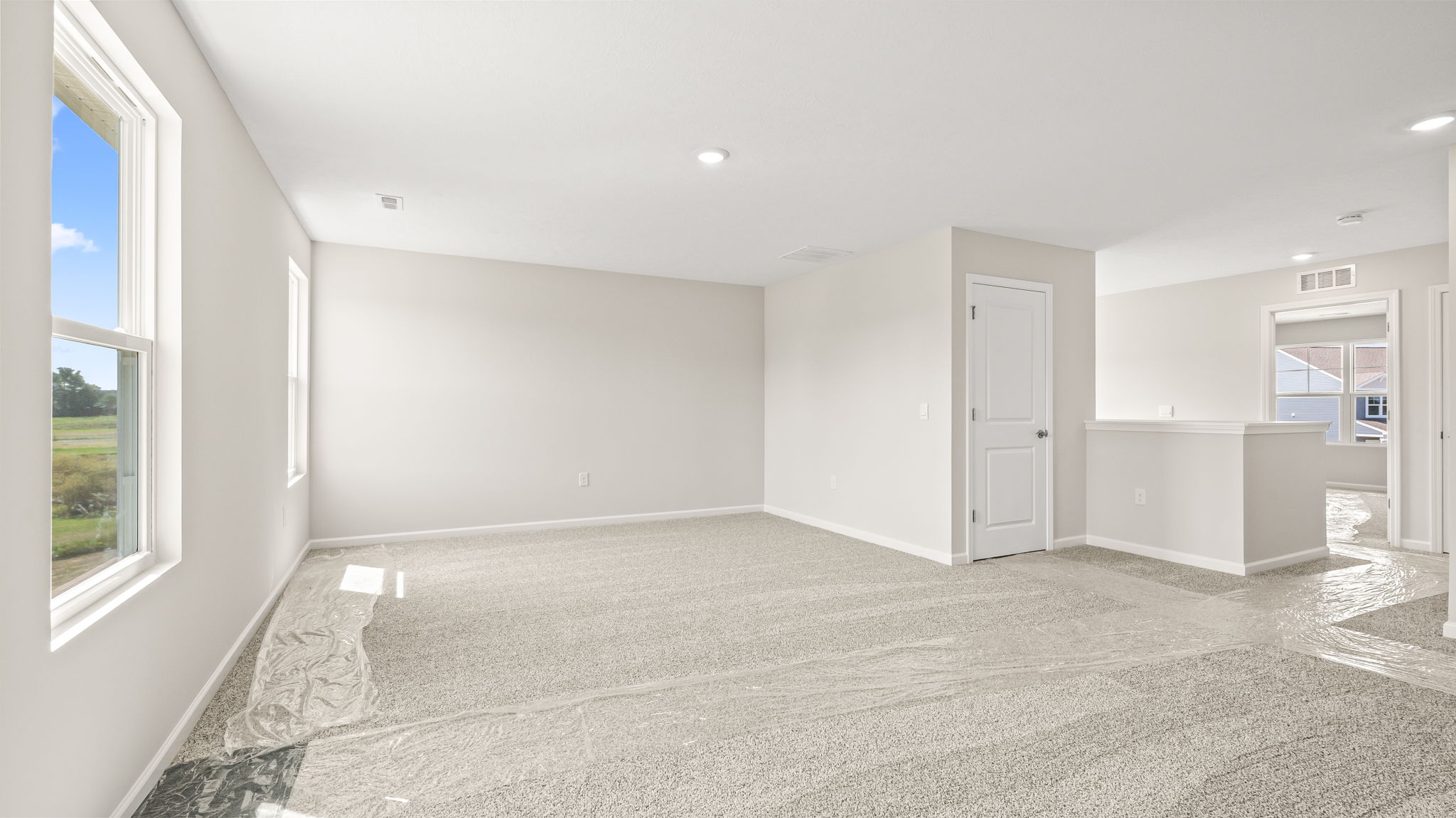 Wide angle image of carpeted loft with two windows