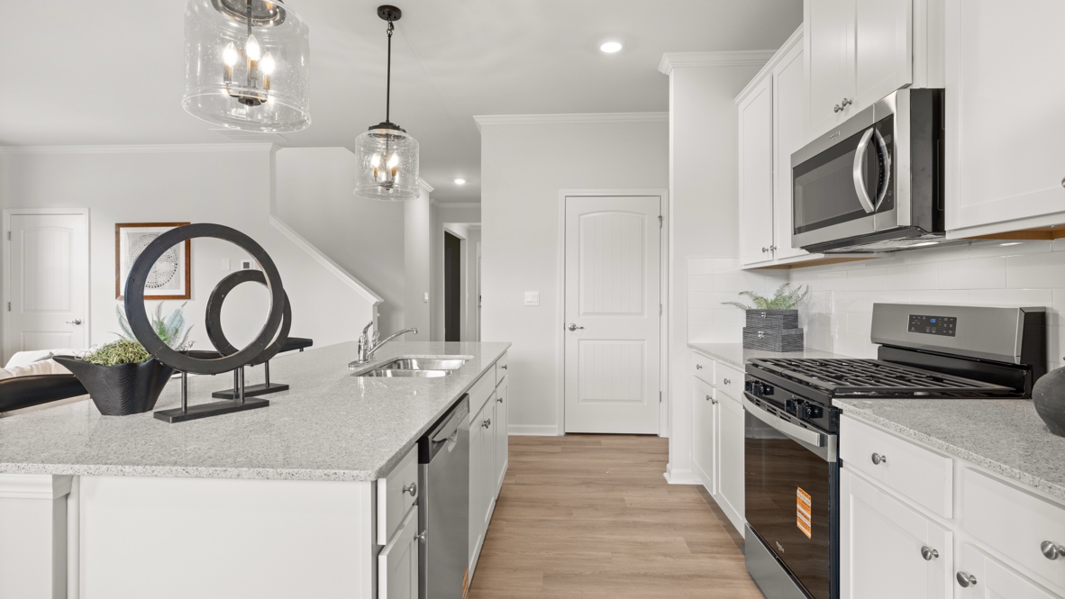 Side view of kitchen with island on the left and oven range between cabinets on the right