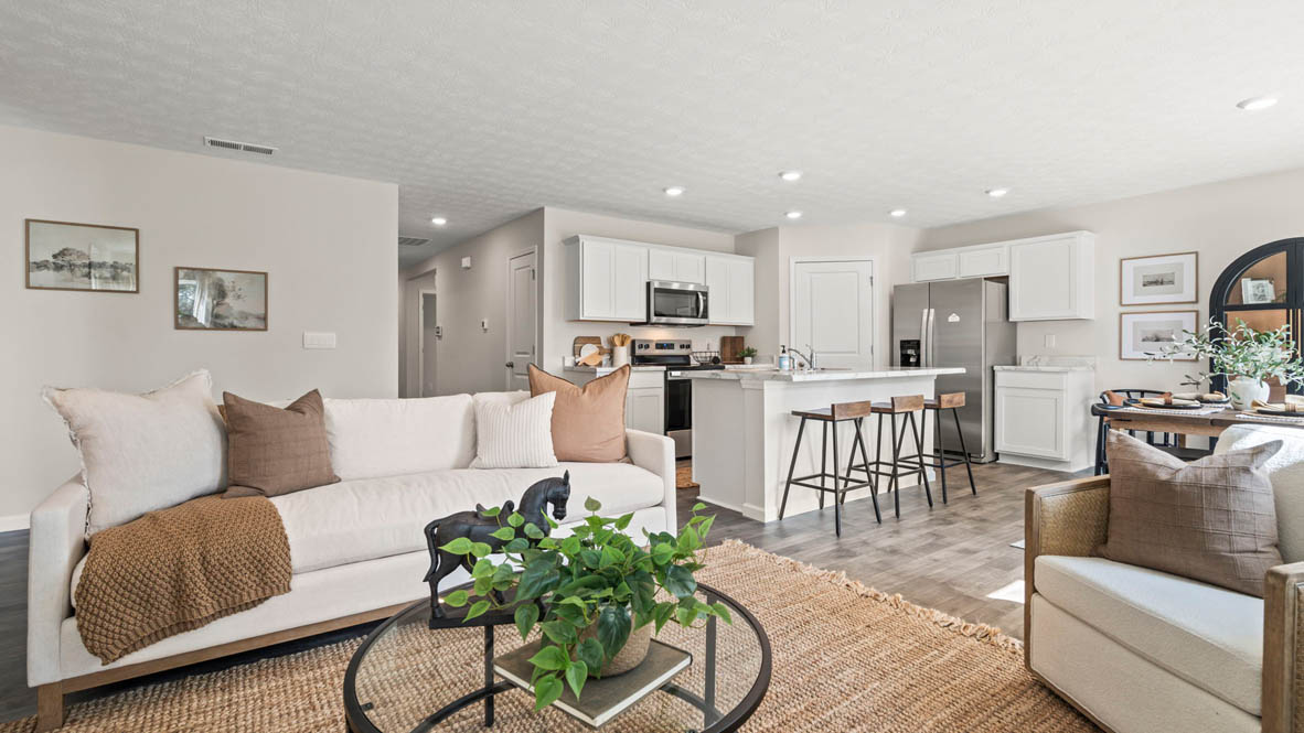 Modern open-concept great room with white cabinets in kitchen and white couch.