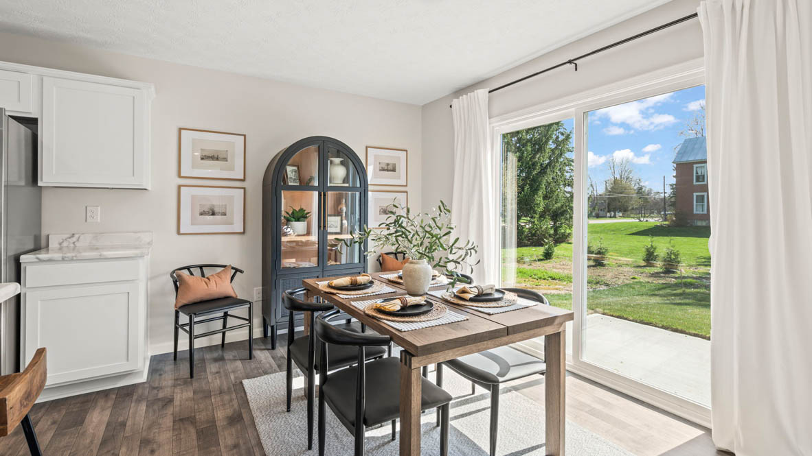 Dining room with wooden table, black cabinet, and large sliding door to porch.