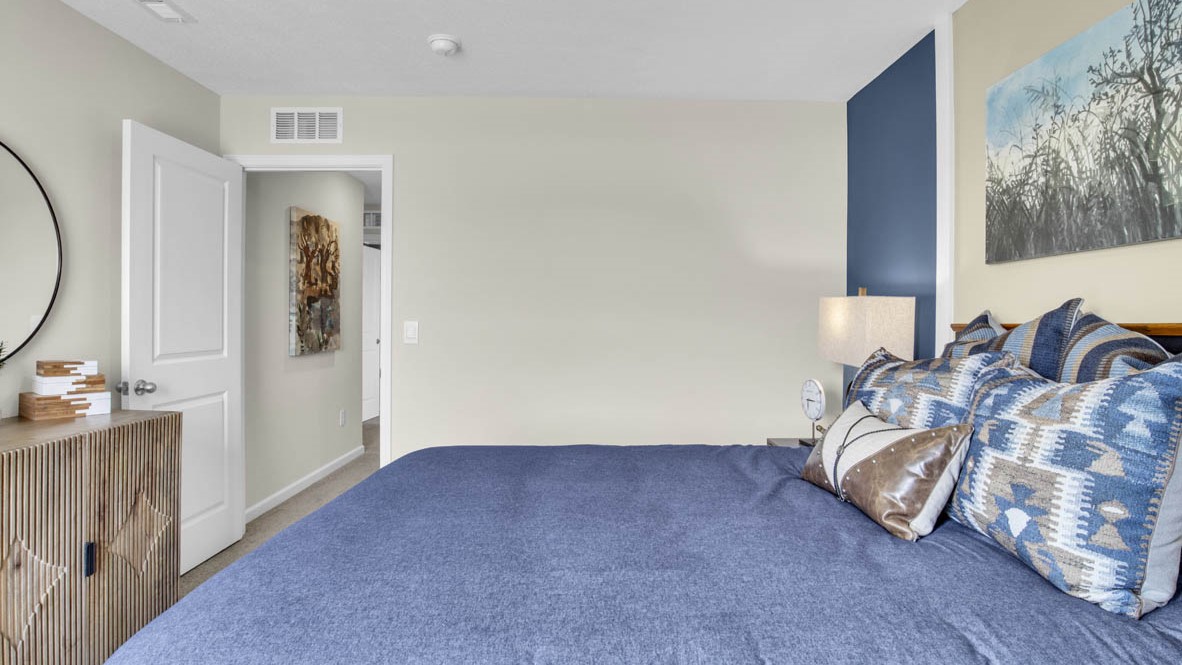 Side view of bed with light blue and earthy bedding.