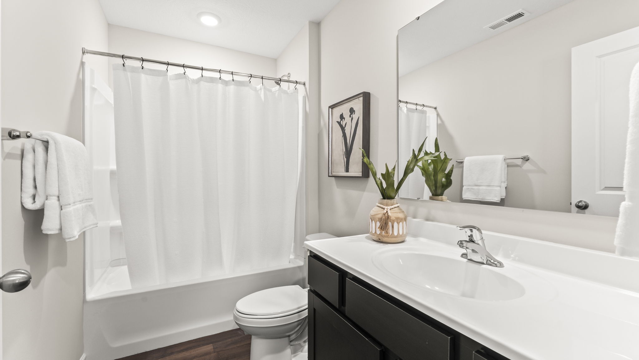 Family full bathroom with stylish vanity, mirror, polished fixtures, cabinets, tub-shower combo