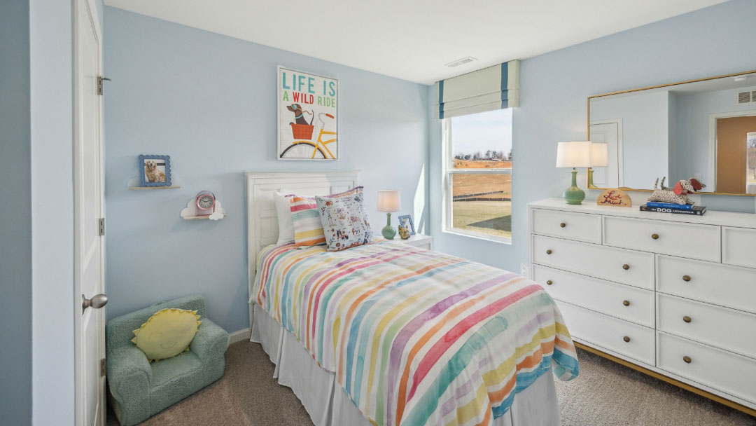 bedroom decorated in colorful decor, featuring light blue walls, white wooden furniture and a window to the right of the bed