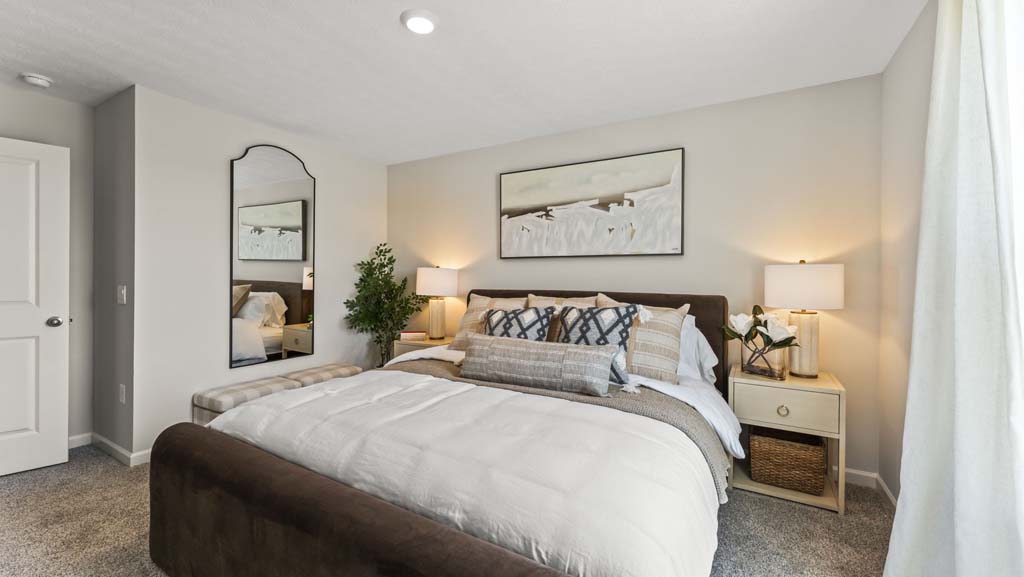 Primary bedroom with brown, tan, and beige bedding with abstract art and mirror on the walls