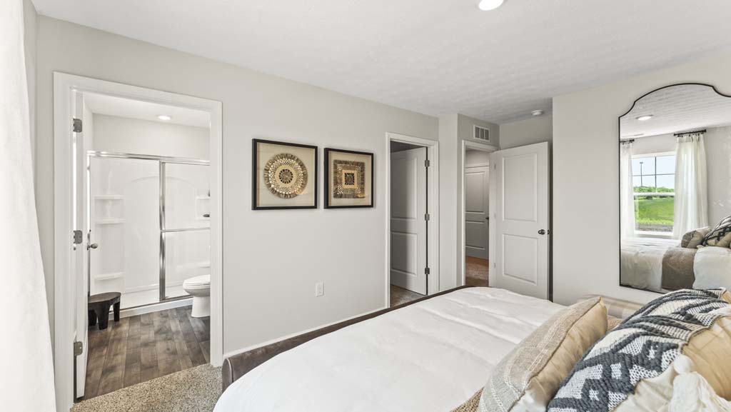 Primary bedroom with with mirror, contemporary art, and peering into primary bathroom