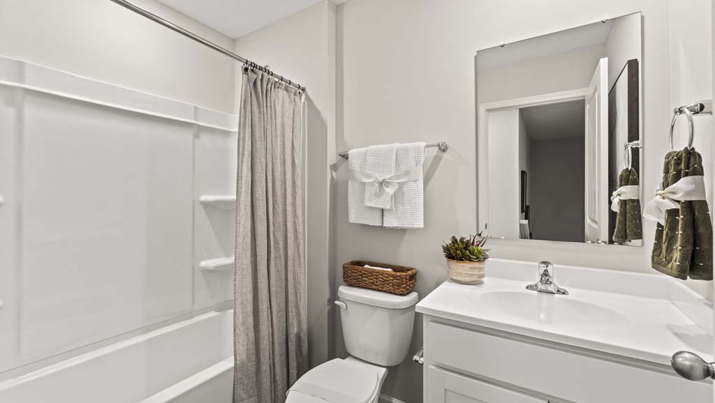Clean white bathroom with tub, shower, toilet, and sink with mirror