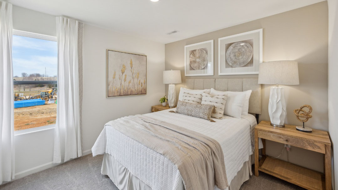 bedroom decorated in white and beige tones, featuring a bed and 2 wooden night stands on each side, with a window on the left wall of the bed