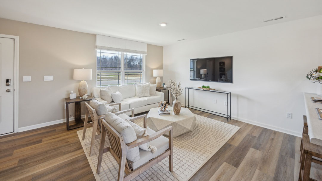 open concept living room with tan and white decor overlooking a TV on the back wall