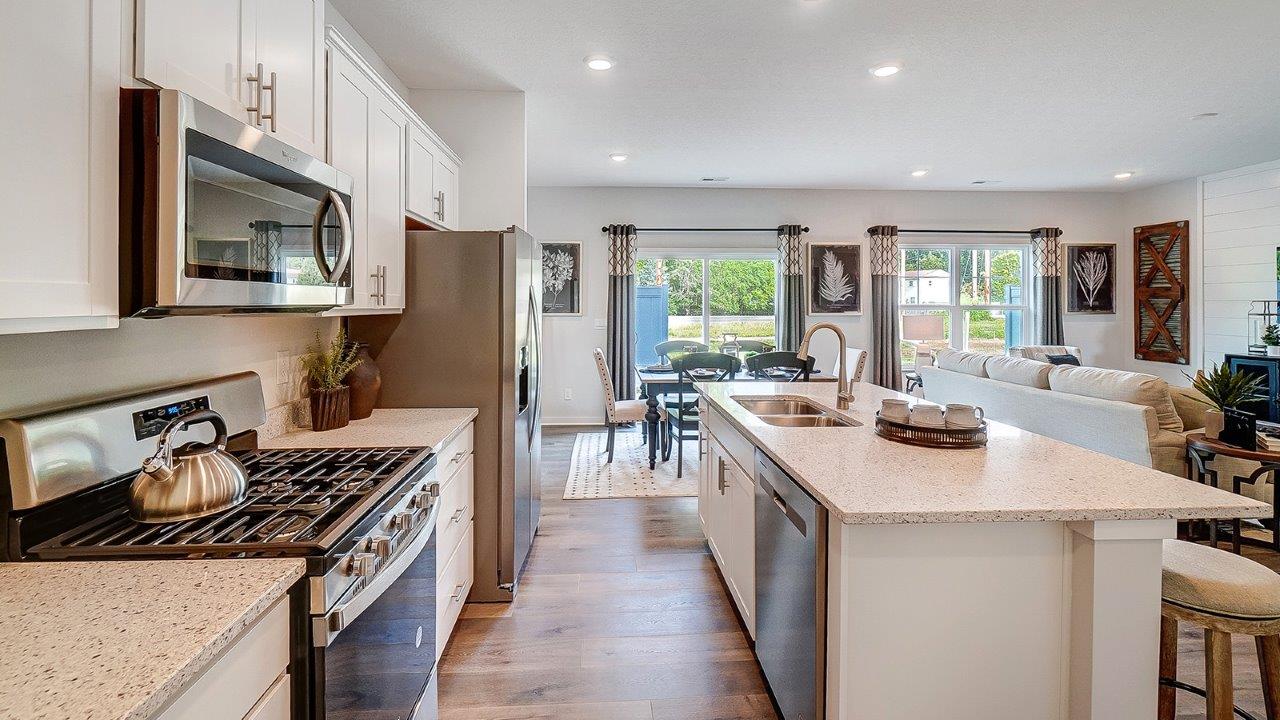 Kitchen with white cabinets and stainless steel appliances and dining room table.
