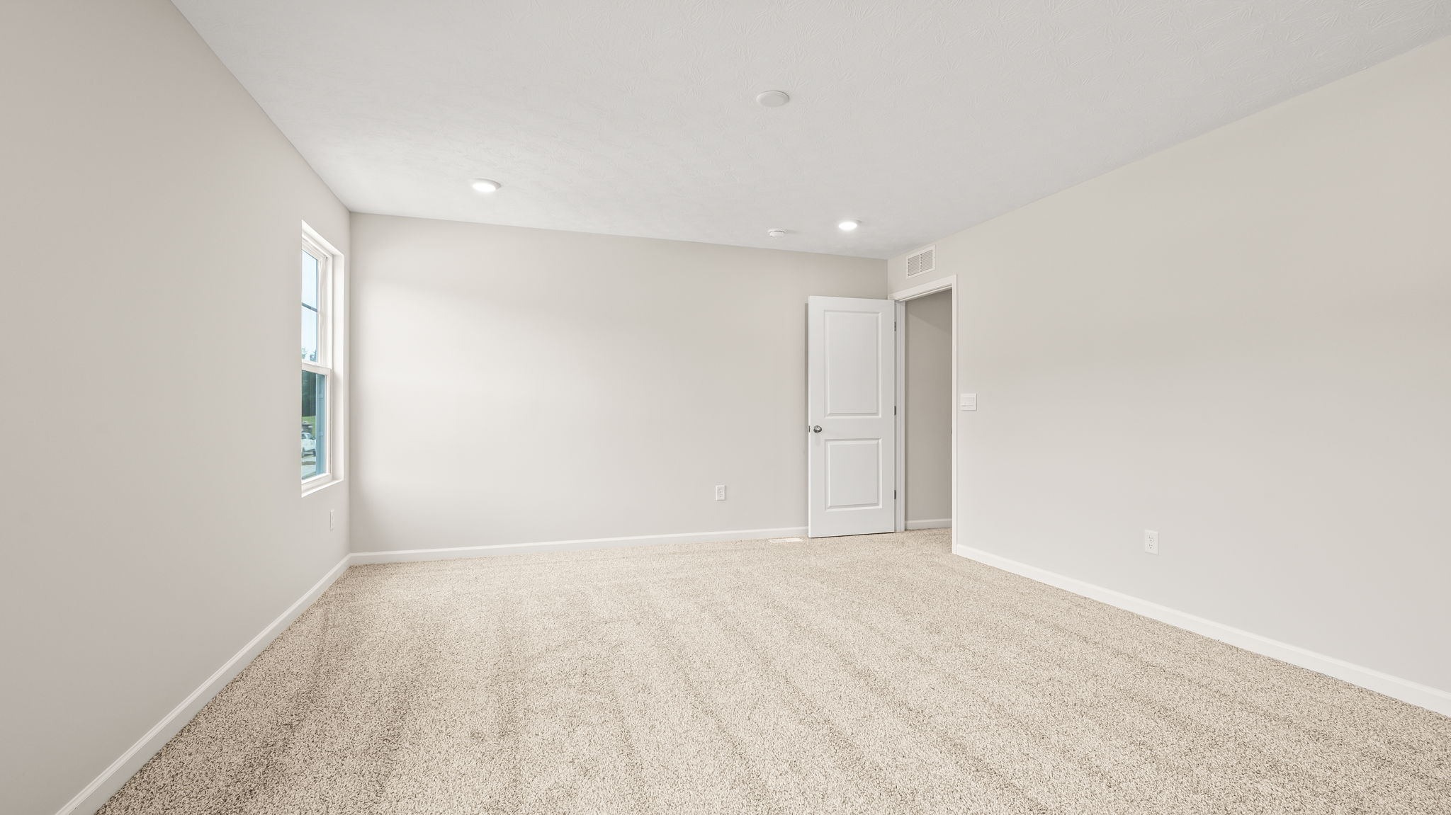 Carpeted primary bedroom with view of door to hallway