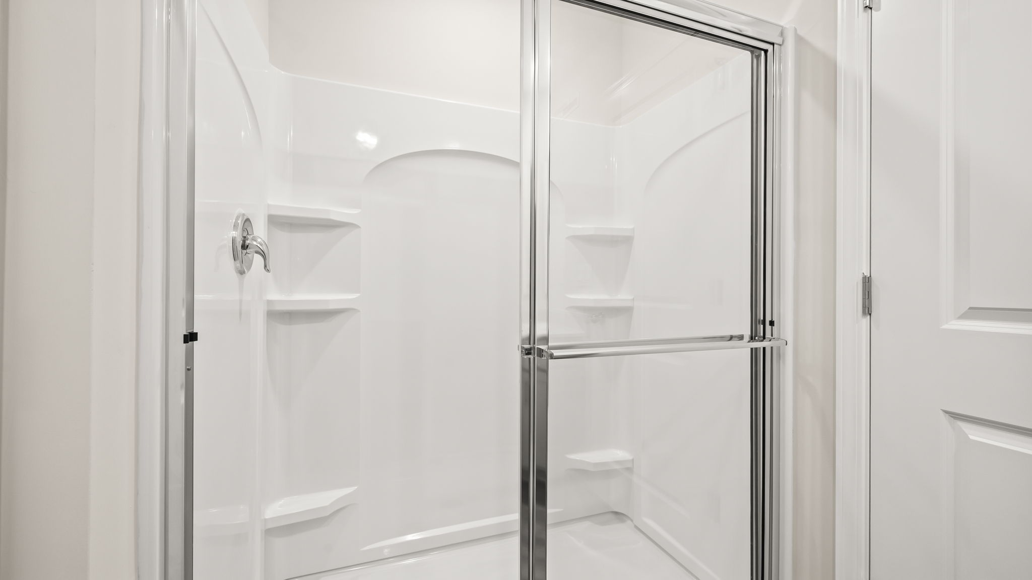 Closeup of glass door shower with tiered shelving