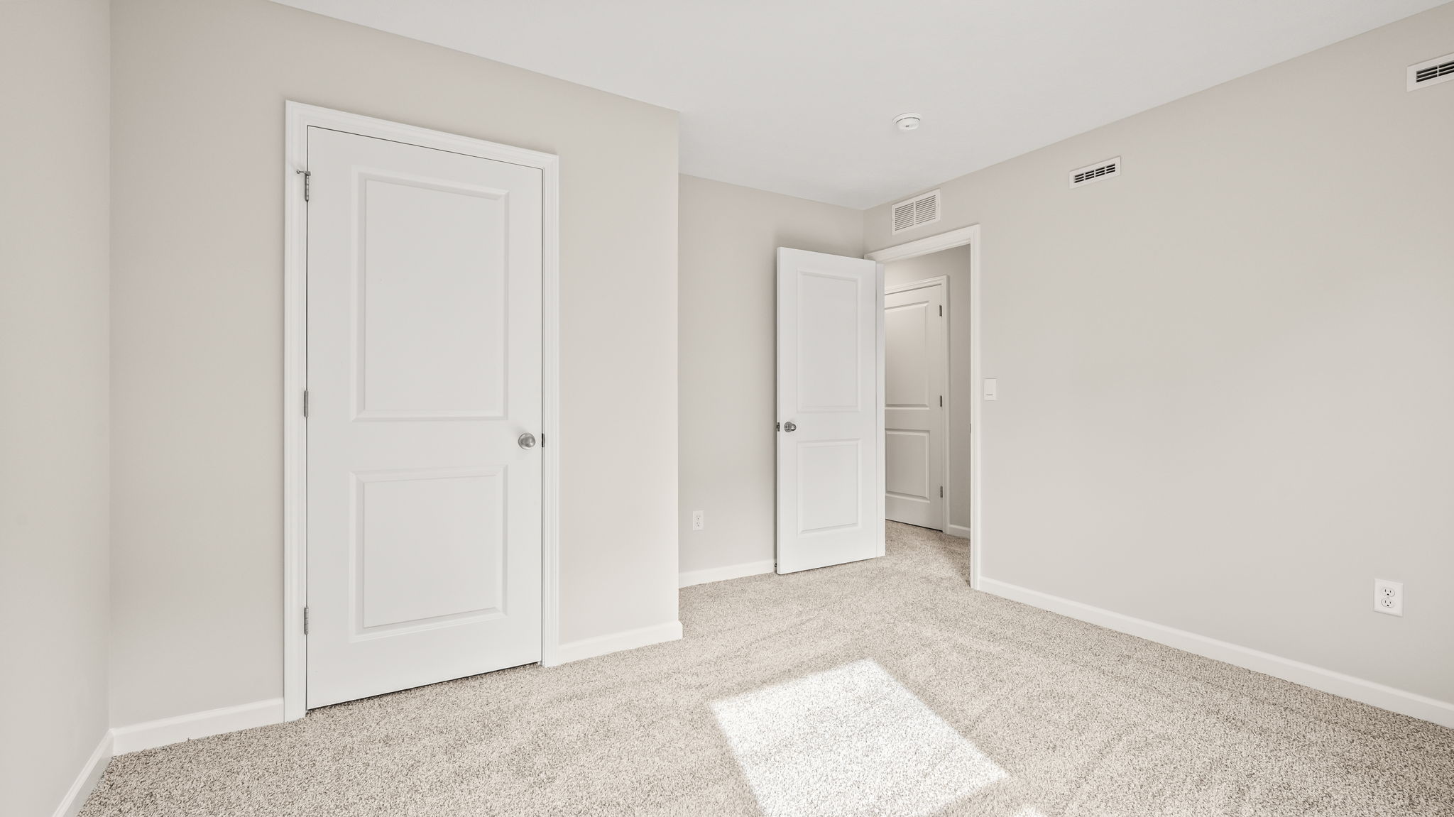 Carpeted bedroom with door to closet and hallway door