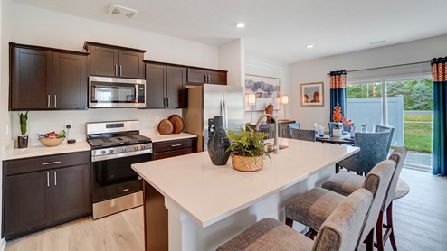 Kitchen with dark cabinets and stainless steel appliances and dining room table.