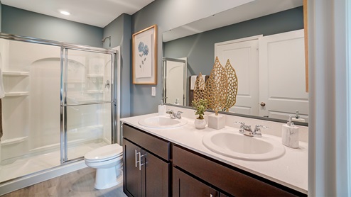 Dual vanity sinks in the primary bedroom with a large mirror.