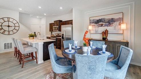 Dining and kitchen with wooden accents and blue and grey chairs.