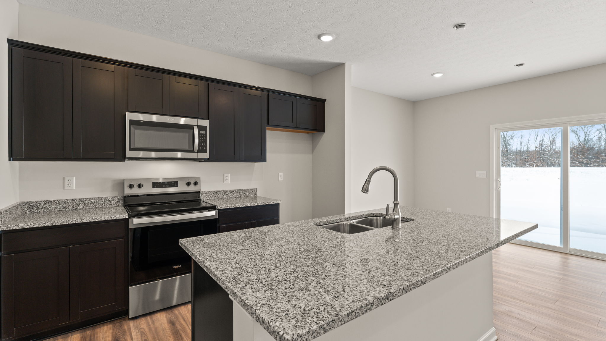 Closeup of kitchen island with cabinetry and appliances in the back.