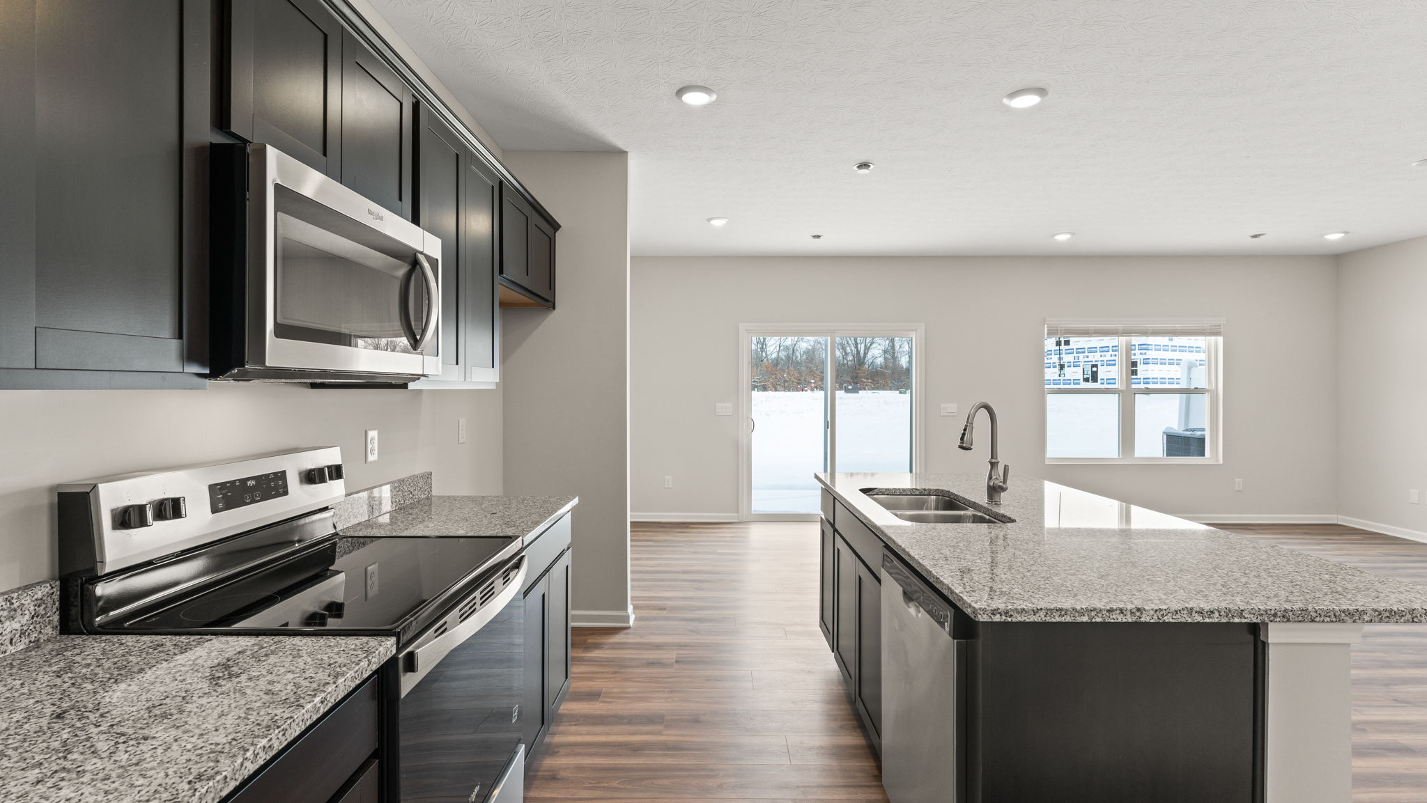 Side view of kitchen with oven range, microwave, dishwasher in-island.