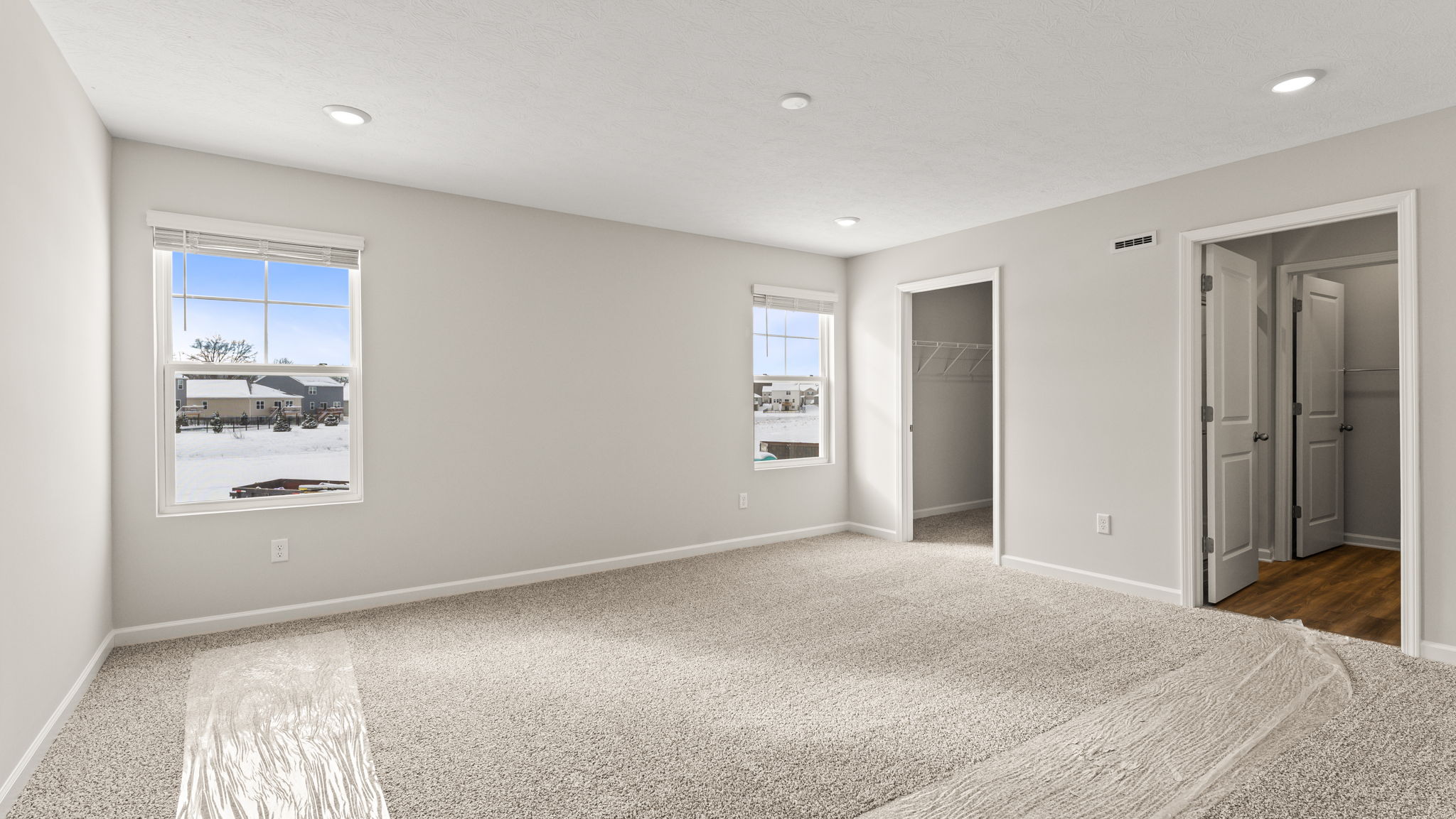 Primary bedroom with two windows, walk-in closet, and door to bathroom
