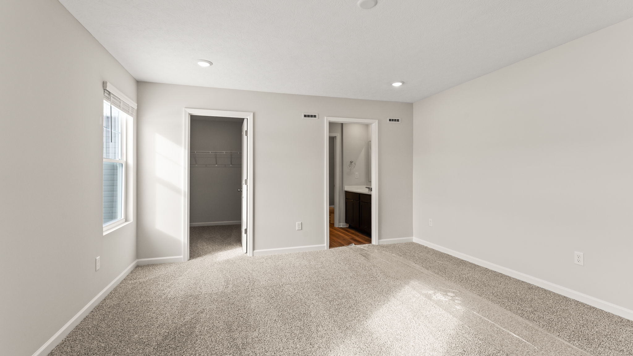 Primary bedroom with window, walk-in closet, and door to bathroom