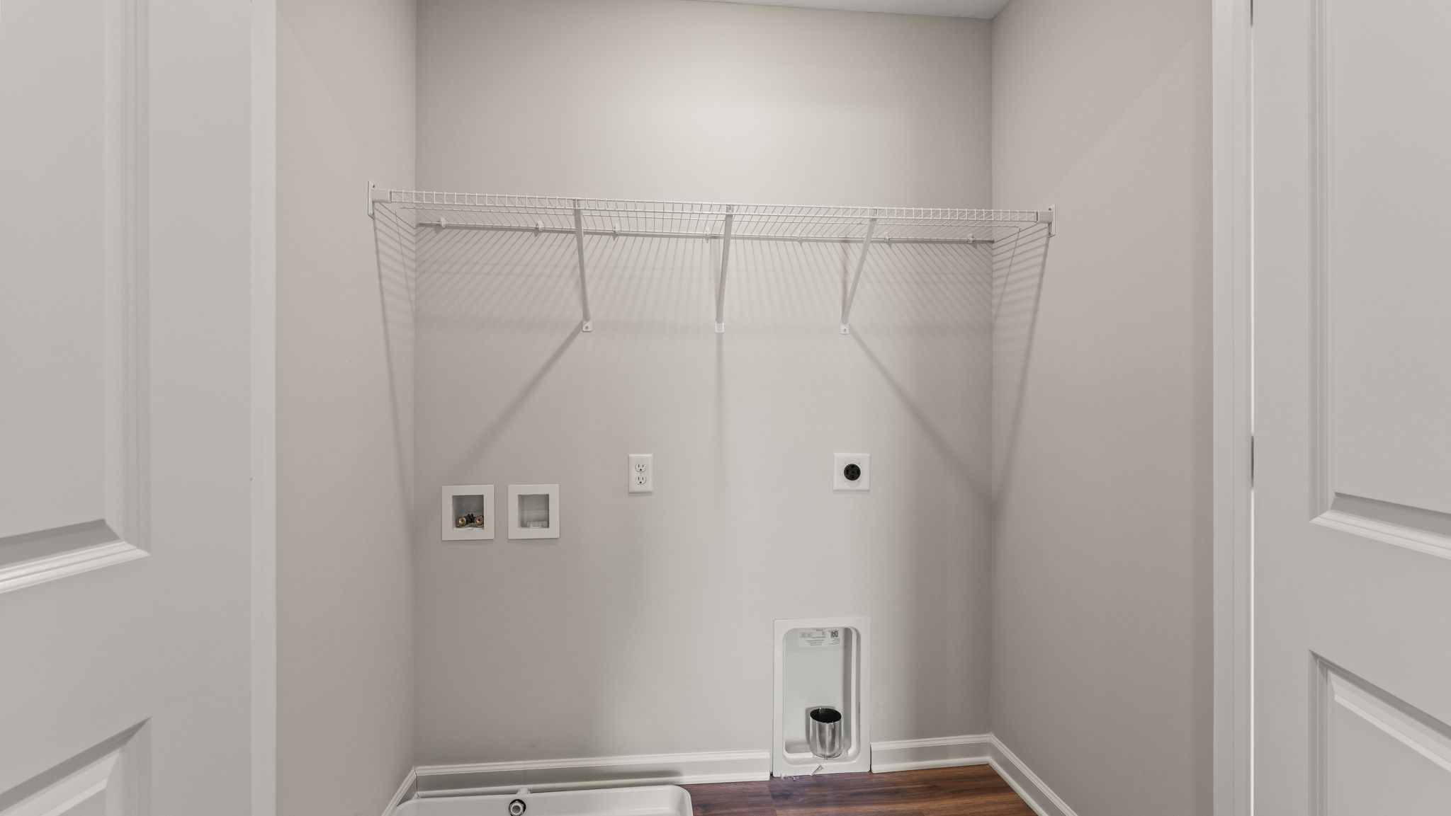 Laundry room with washer/dryer inlets and wire rack shelving.