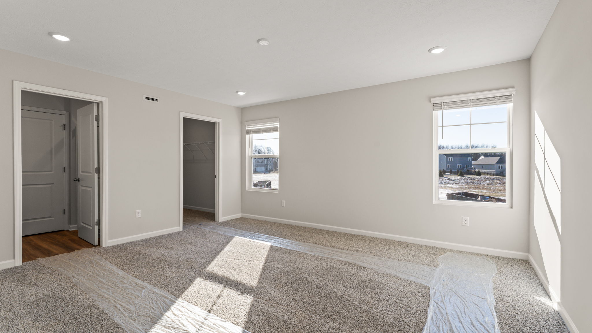 Primary bedroom with two windows, door to hallway, and primary bathroom