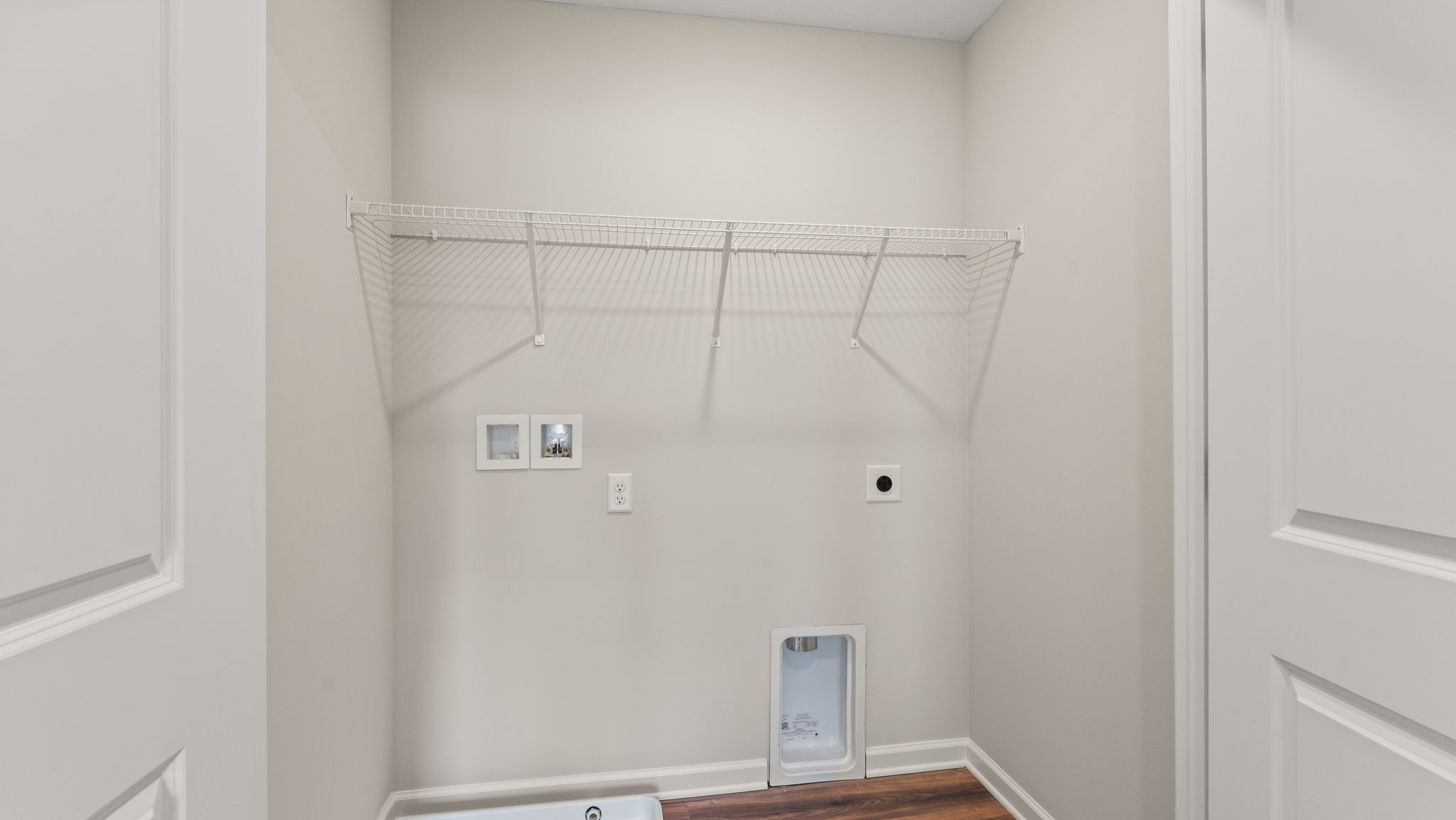 Laundry area with wire rack shelving and washer/dryer inlets.
