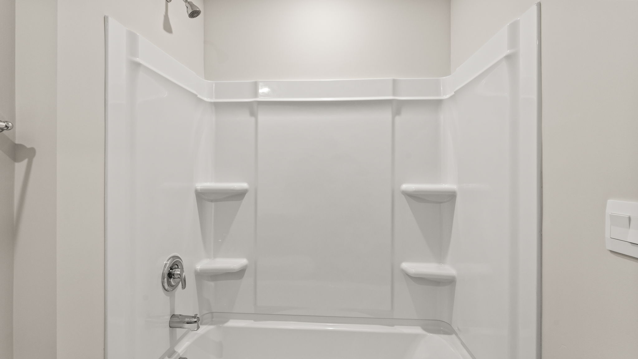 Bathroom tub/shower combo with tiered shelving.