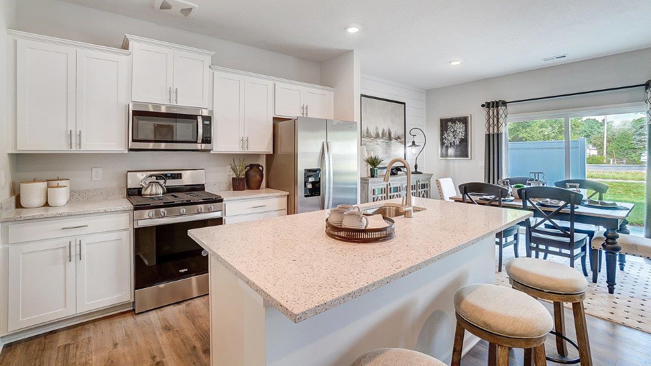 Kitchen with white cabinets and stainless steel appliances and dining room table.