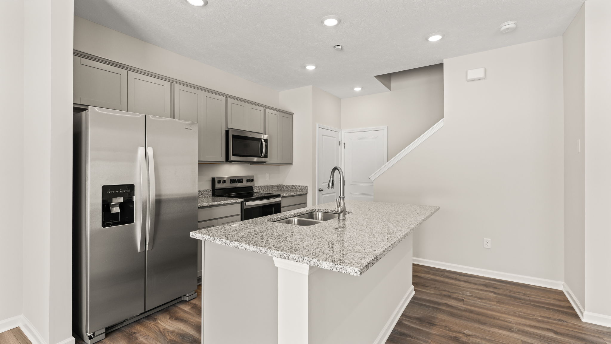 Three-quarter view of kitchen with appliances, grey cabinetry, and island