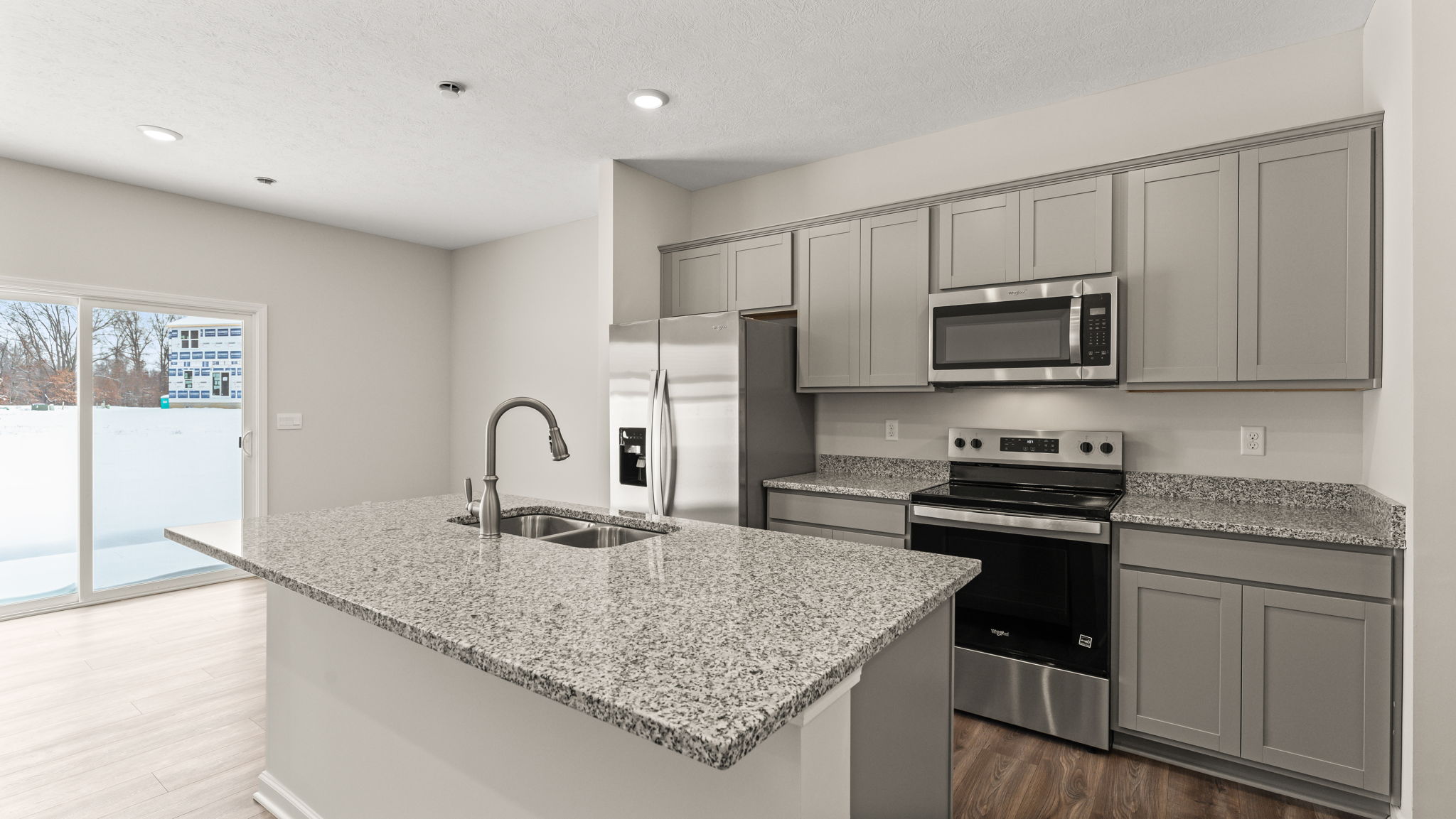 Three-quarter view of kitchen with granite countertops, elkins crown cabinetry, appliances, and island.