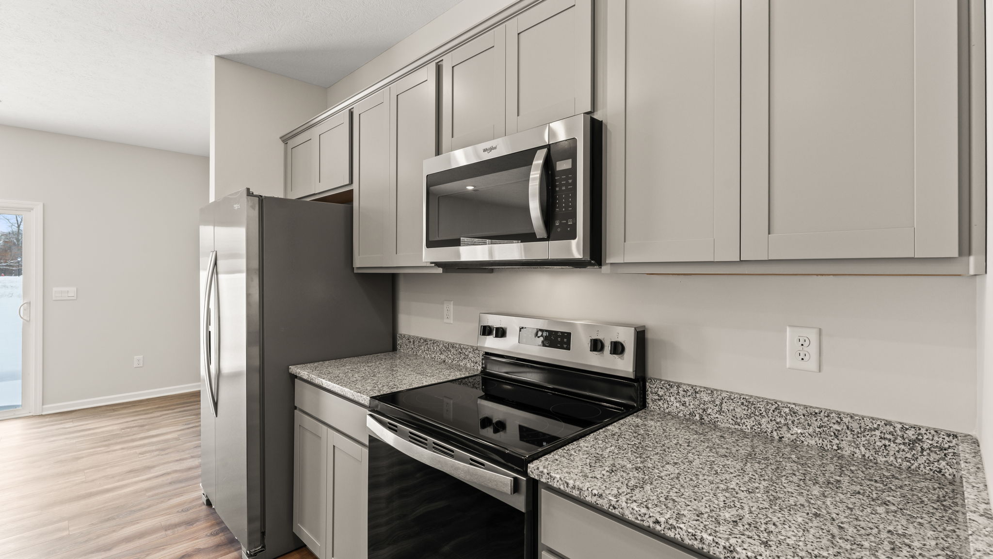 Closeup of oven range and microwave between granite counterops and elkins cabinetry.