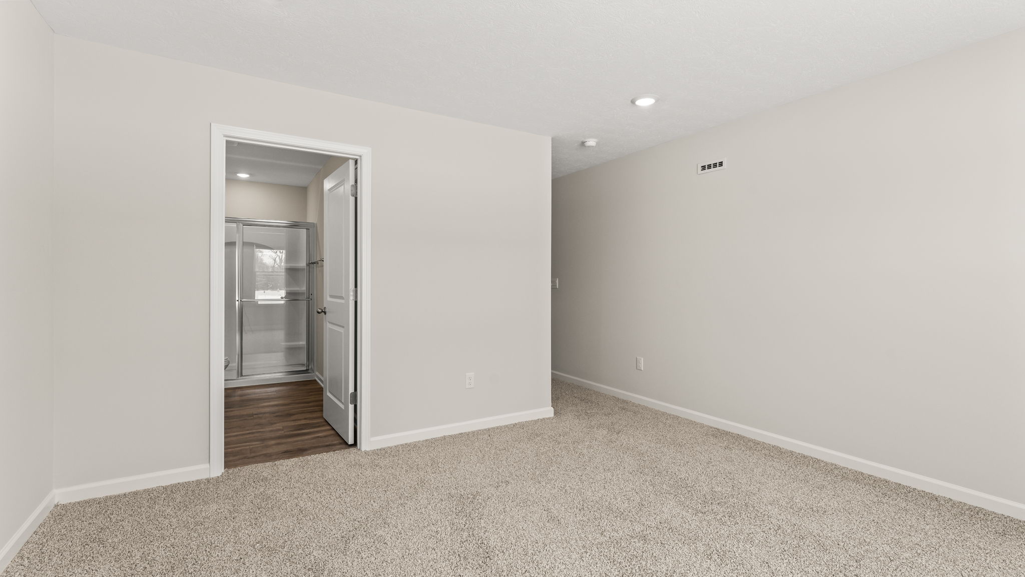 Primary bedroom with view into primary bathroom