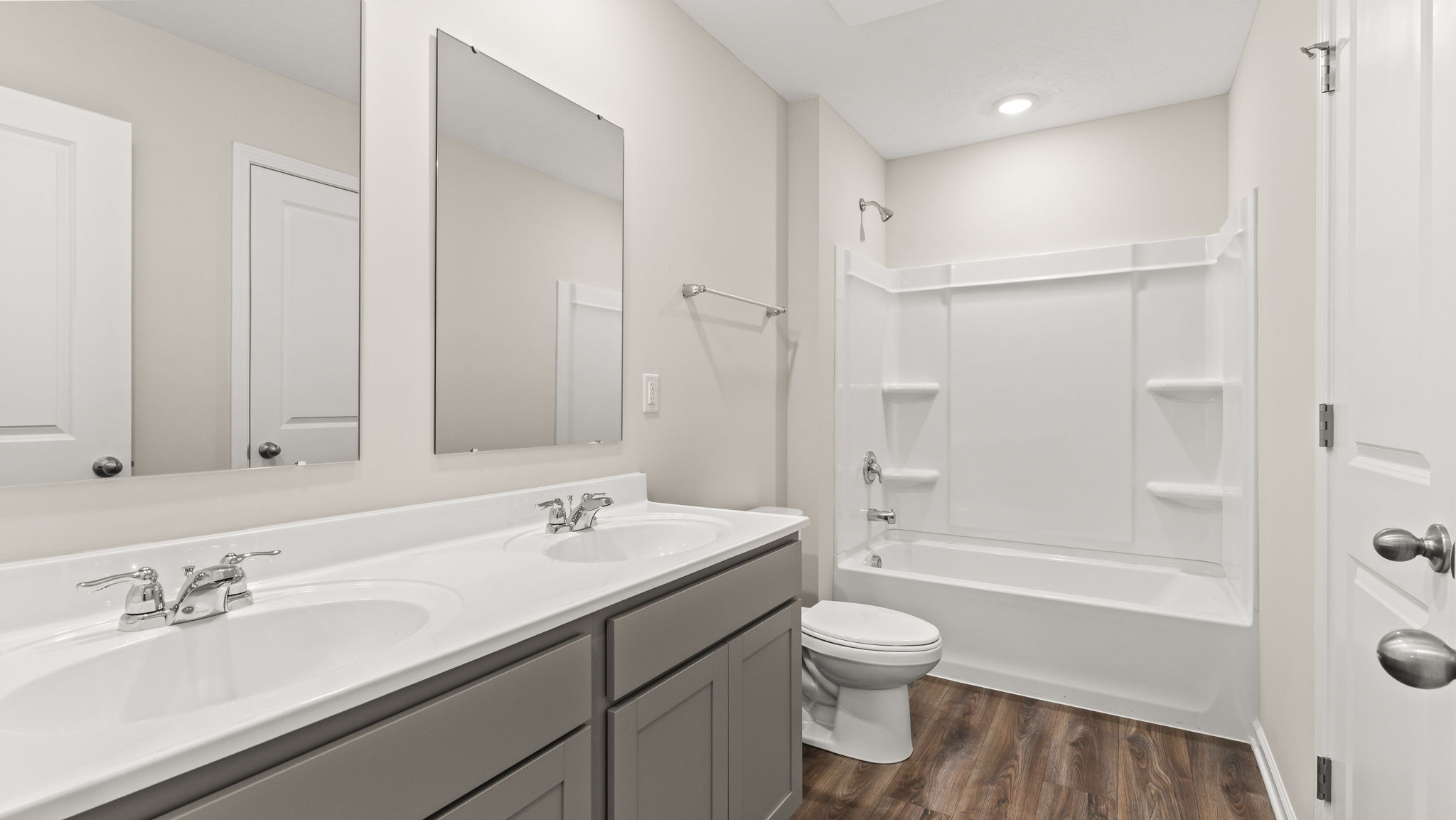 Bathroom with dual-sink vanity, toilet, tub, and shower