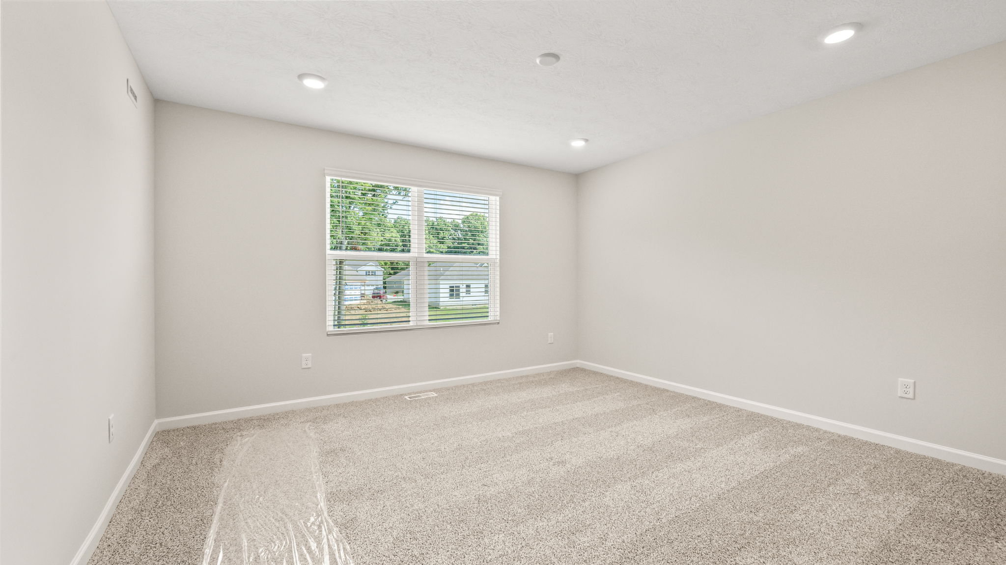 Carpeted primary bedroom with window