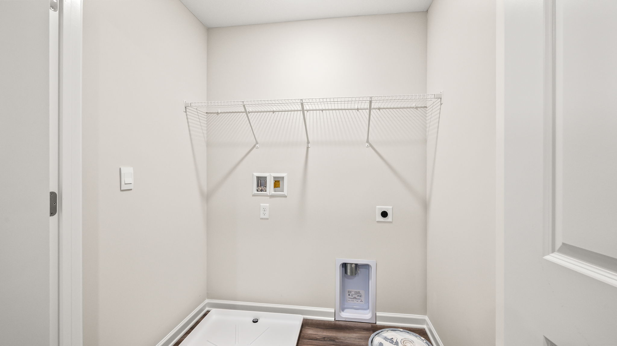 Laundry area with wire rack shelving and washer/dryer inlets