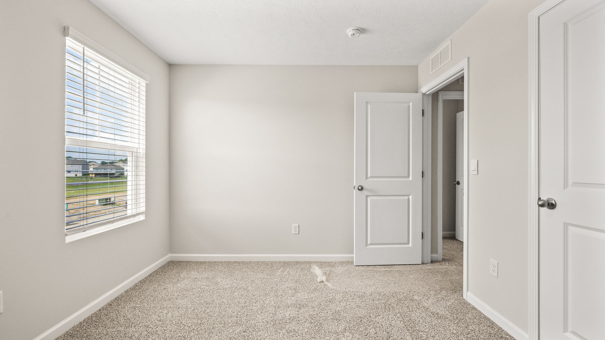 Carpeted bedroom with window and hallway door