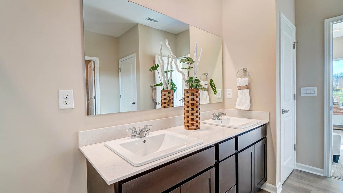 Private bathroom off primary with dual vanity sinks, large mirror, and elegant accents.