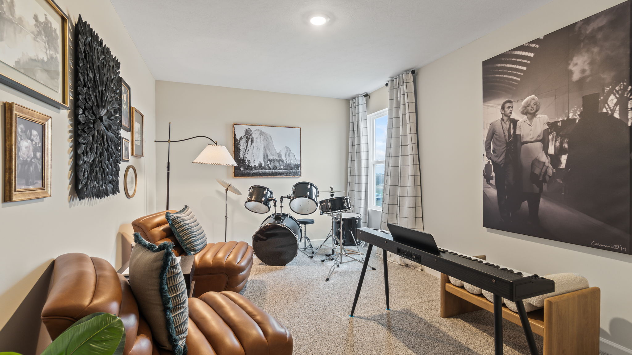 Bedroom 4 dressed as a music room with drum set, keyboard piano, chairs, and print art on walls.