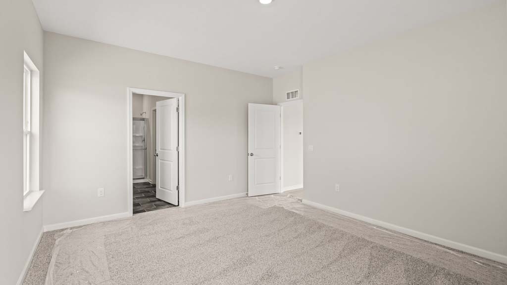 Primary bedroom with view of primary bathroom and hallway